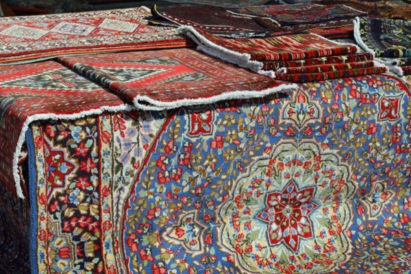 stall of many fine-made oriental rugs for sale in the open-air market with no people in the frame
